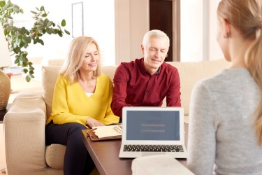 Couple sitting on a couch sitting across from a female advisor at a desk
