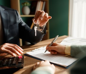 Signing mortgage application, another person holds key