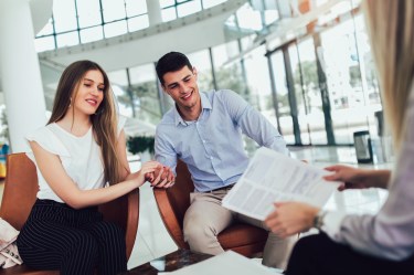 Young couple sitting across desk from a financial professional or lender looking at documents
