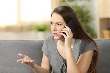Woman looking frustrated while arguing on a phone call, representing poor customer service and unresolved banking issues.