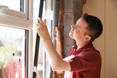 Man in a red shirt installing new window in a home