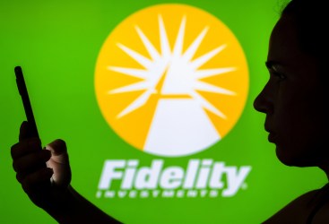 Silhouette of a person holding a smartphone in front of a bright green background displaying the Fidelity Investments logo.